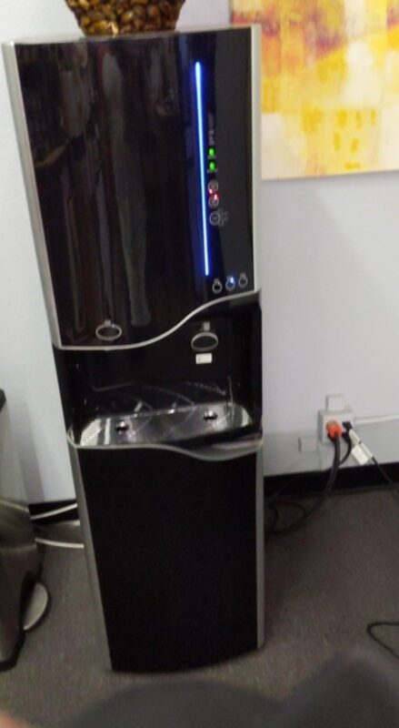 Black bottleless water cooler installed in a commercial office