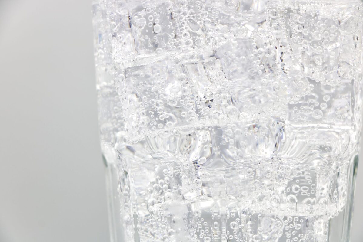 Close-up of sparkling water with bubbles and ice in a glass